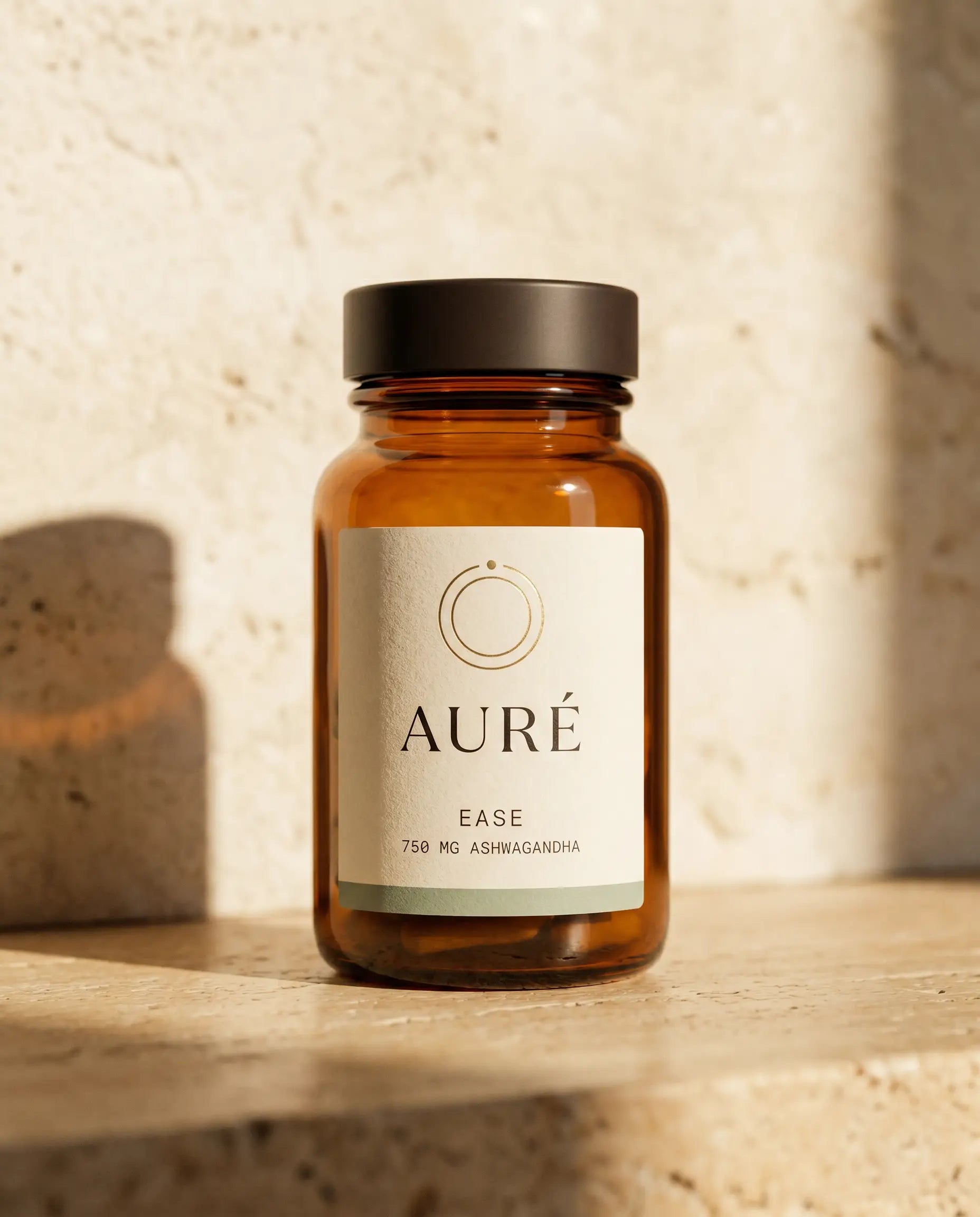 AURÉ Ease — honey-amber glass bottle, cream label printed with 750 mg ashwagandha